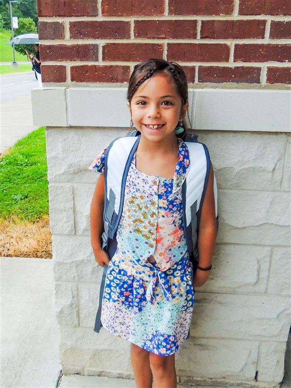 girl student smiling against a brick pillar